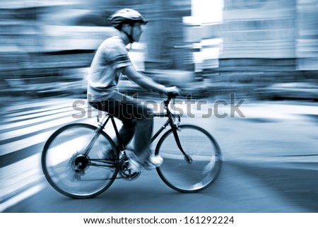 cyclist in traffic on the city roadway  motion blur and blue tonality
