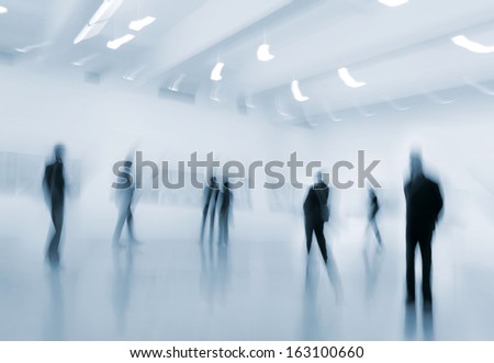 abstakt image of people in the lobby of a modern art center with a blurred background and a blue tonality