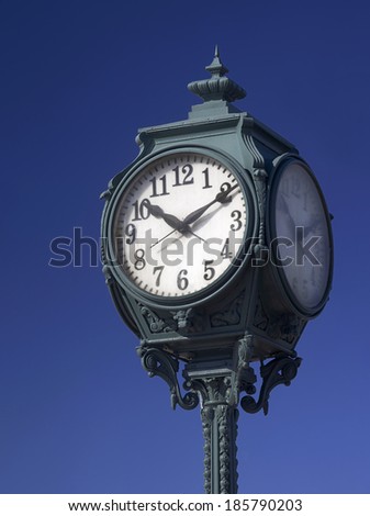 urban street antique clock with metal ornaments closeup on blue sky background