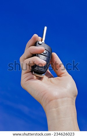 car key in hand on blue sky background