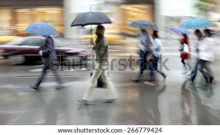 business people walking in the street on a rainy day motion blurred