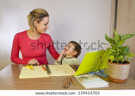 Happy woman helping small kid write