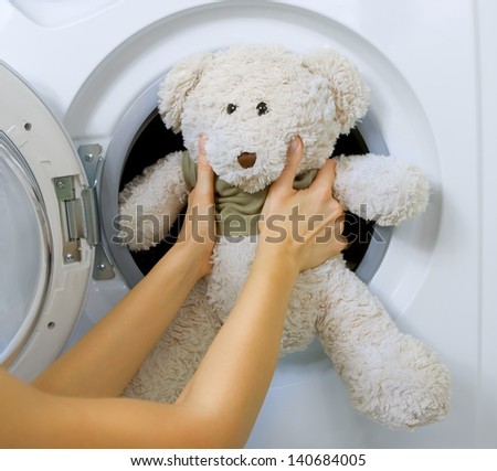 woman loading fluffy toy in the washing machine