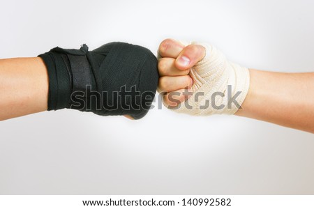 Hand in a white glove and hand in a black glove clasped arm wrestling, good and evil opposition