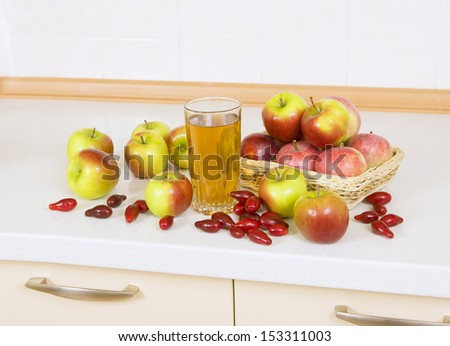 Apple juice in a glass on a table with apples and Cornelian cherry
