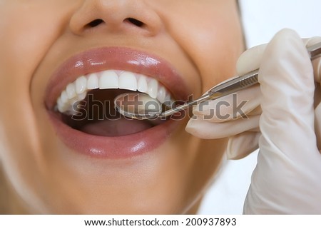 Close-up of female patient having her teeth examined by dentist, visit to the dentist, oral checkup with mirror