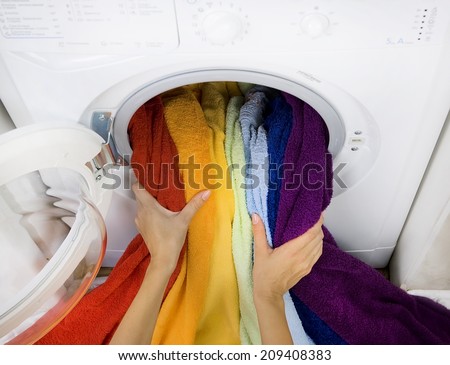 woman taking color laundry (clothes) from washing machine