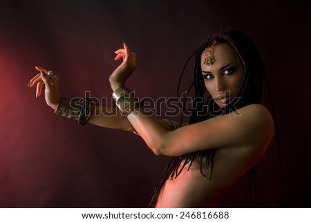 Fashion Beauty and stylish hair (dreadlocks). Spirituality dance. Beautiful Sexy Woman With Luxury glossy gold eastern Makeup danceing tribal fusion. Indian accessories (oriental jewelry)