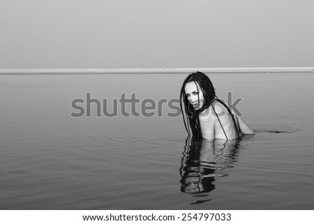 Beautiful Black and white atmospheric melancholy picture: graphic minimalism, beautiful sexy caucasian girl with slim body and stylish hair posing on the sea beach