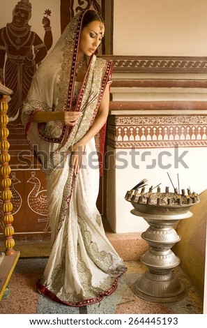 Beautiful young indian woman in traditional clothing with incense, bridal makeup and oriental jewelry. Girl bollywood dancer in Sari, eastern palace. Beautiful princess praying. Eastern fairy tale