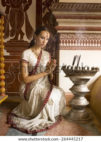 Beautiful young indian woman in traditional clothing with incense bridal makeup and oriental jewelry. Girl bollywood dancer in Sari, eastern palace. Beautiful princess praying. Eastern fairy tale