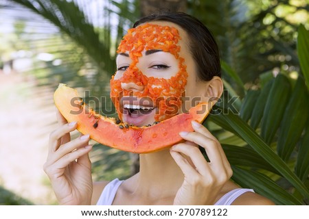 Beautiful caucasian woman having fresh fruit papaya natural facial mask apply, antioxidant skin care and wellness. Facial vitamin mask of papaya slices at spa salon (outdoors). Healthy exotic food