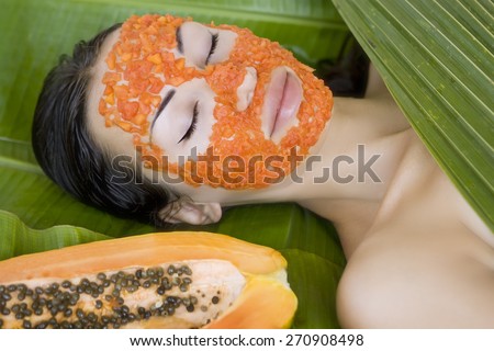 Beautiful caucasian woman having fresh papaya natural facial mask apply, skin care and wellness (outdoors). Facial vitamin mask of papaya slices at spa salon