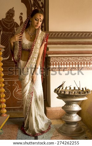 Beautiful young indian woman in traditional clothing with bridal makeup and oriental jewelry. Beautiful Girl bollywood dancer in Sari posing outdoor near the eastern palace