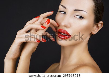 Sexy Young Beautiful Brunette Girl with Red Lips and Red Nail Polish, Bright Glistening  Shining Make-up Closeup on Dark Background (black)