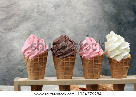 Vanilla frozen yogurt or soft ice cream in waffle cone and strawberry, raspberry and chocolate softice cream