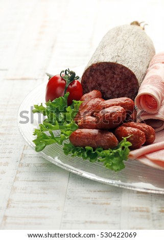 Food tray with delicious salami, pieces of sliced ham, sausage, tomatoes, salad and vegetable - Meat platter with selection - Cutting sausage and cured meat on a celebratory table.
