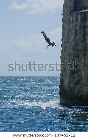 ACRE, ISRAEL - JUNE 27, 2009: Young mn jumps to the sea from the top of the ancient walls of Acre, Israel. Acre is one of the oldest continuously inhabited sites in the world.