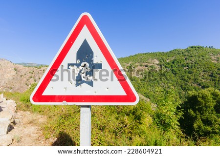 Road sign punched by bullet holes, in the Gorges de Spelunca, in Corsica, France