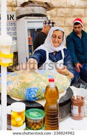 NAZARETH, ISRAEL - December 19, 2014: A woman preparing pita bread, in a Christmas market food stall, in Nazareth, Israel