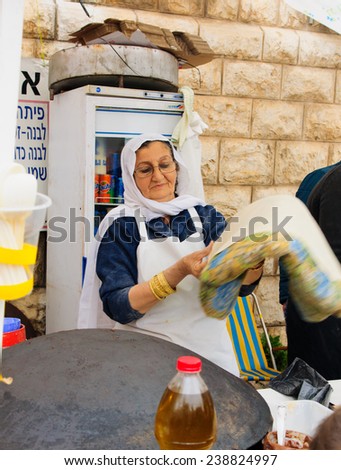 NAZARETH, ISRAEL - December 19, 2014: A woman preparing pita bread, in a Christmas market food stall, in Nazareth, Israel