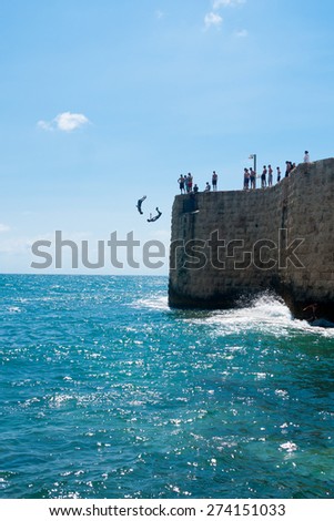 ACRE, ISRAEL - JUNE 27, 2009: Young men jumps to the sea from the top of the ancient walls of Acre, Israel. Acre is one of the oldest continuously inhabited sites in the world.