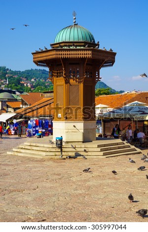 SARAJEVO, BIH - JULY 05, 2015: Typical street scene, with the Sebilj fountain, local businesses, locals and tourists, in Sarajevo, Bosnia and Herzegovina