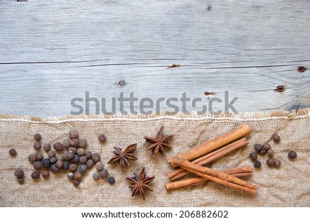 Spices background - cinnamon, pepper and anice on burlap and wood
