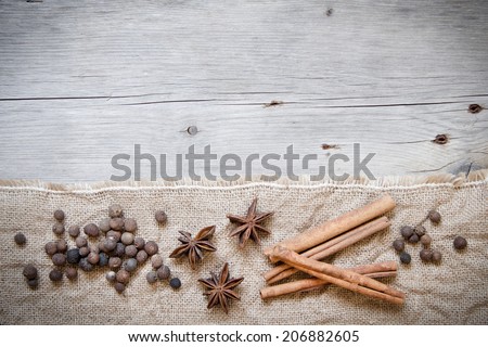 Retro spices background - cinnamon, pepper and anice on burlap and wood