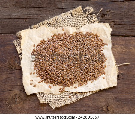 Pile of flax seeds on a wooden background