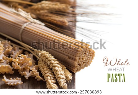Whole wheat italian pasta with wheat spikes on wood