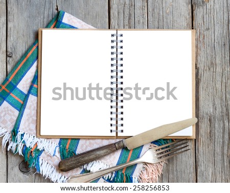 Blank cooking recipe book with fork, knife an napkin on wooden table