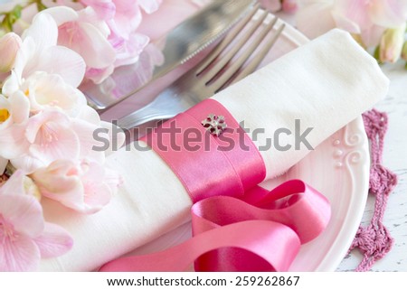 Festive wedding table setting with pink flowers and ribbon