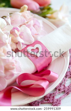 Festive wedding table setting with pink flowers and ribbon