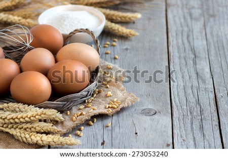 Chicken eggs, wheat and flour on the old wood