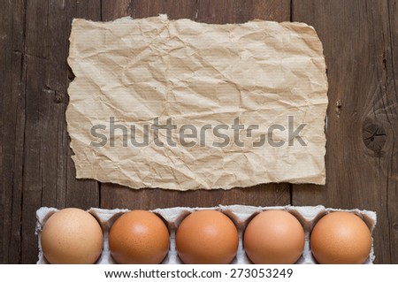 Chicken eggs in the package and craft paper on the old wooden table
