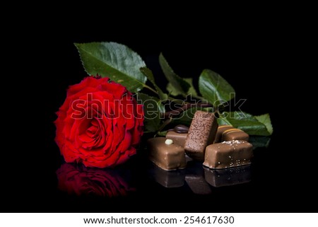 Red rose and chocolate on black background.