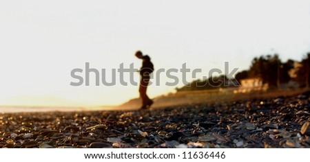 Image of some pebbles with a man in the background as a silhouette late in the day