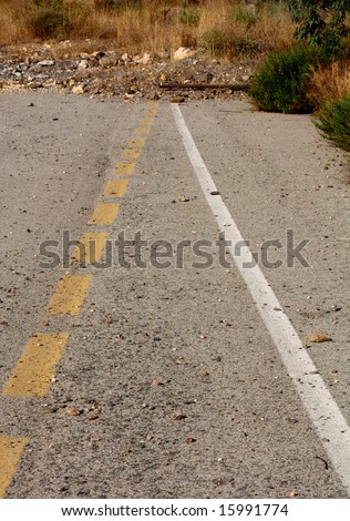 A broken yellow line and a white line converging at an area with rubble. Concept - the end of the road. Going Nowhere.