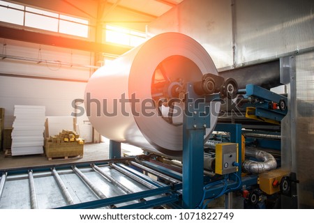 Industrial galvanized steel roll coil for metal sheet forming machine in metalwork factory workshop, sunlight toned