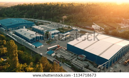 Aerial view of warehouse storages or industrial factory or logistics center from above. Aerial view of industrial buildings and equipment machines at sunset, toned