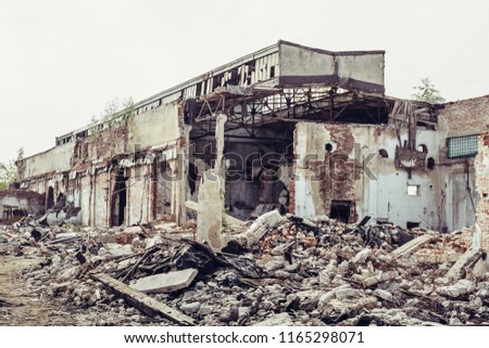 Ruined abandoned industrial building with large pills of concrete garbage, aftermath of natural disaster, hurricane, earthquake or war, toned