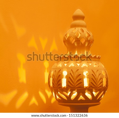 Closeup Of A Decorative North African Terracotta Lamp, Casting Light On An Orange Wall.