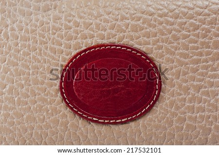 A red woven label sewn into seamed brown leather