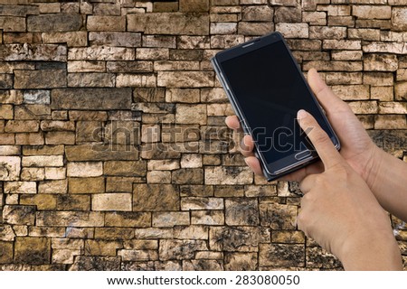 Mobile phone in hand on stone wall background