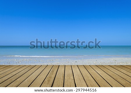 Blue sea & sky background with empty wooden deck table ready for product display montage.