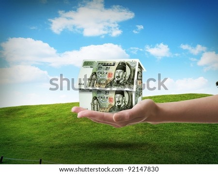 Hand holding money in green grass blue sky