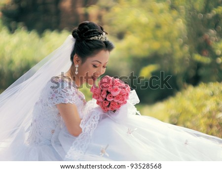 Beautiful Asian bride in semi formal gown with bouquet of wild flowers