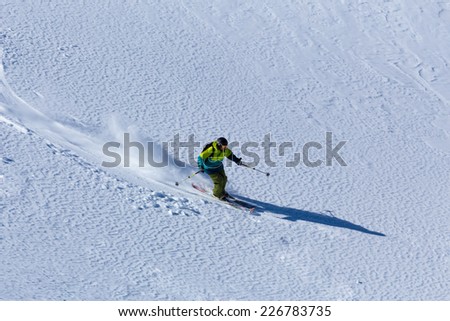 Skier rides through the untouched snow field leaving a trail of snow.