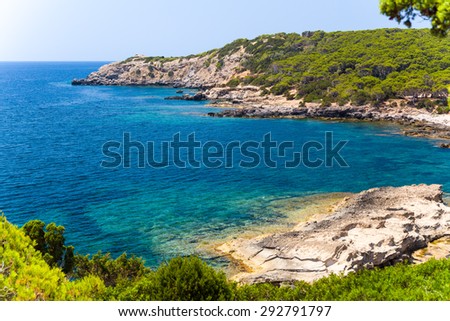 View of the rocky cliffs and clear sea under the bright sun. Sardinia, Italy.